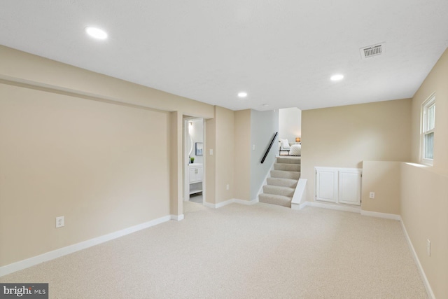 basement featuring recessed lighting, light colored carpet, stairway, and baseboards
