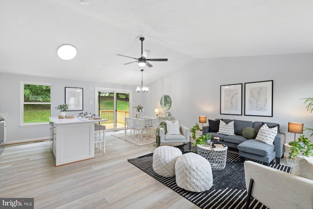 living room featuring ceiling fan, light wood-style flooring, plenty of natural light, vaulted ceiling, and a chandelier