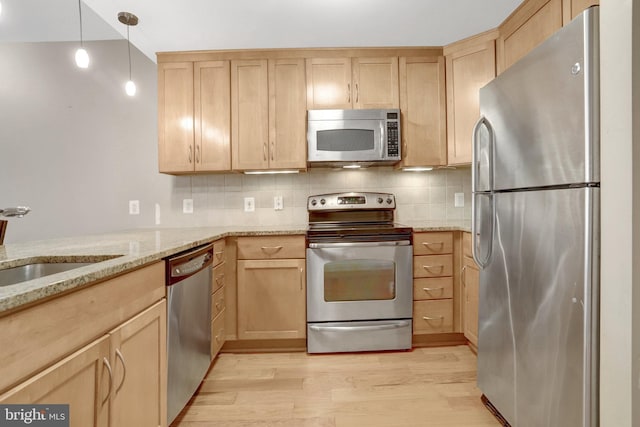 888 N Quincy St Unit 407, Arlington, VA 22203 - kitchen featuring appliances with stainless steel finishes, light brown cabinetry, light wood finished floors, light stone counters, and backsplash