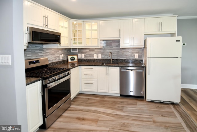 6137 Leesburg Pike Unit 101, Falls Church, VA 22041 - kitchen featuring stainless steel appliances, a sink, decorative backsplash, dark stone counters, and crown molding