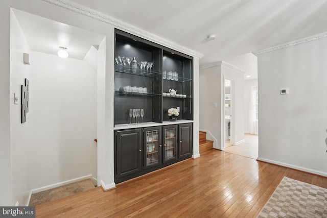 bar featuring light wood-style floors, baseboards, and stairs