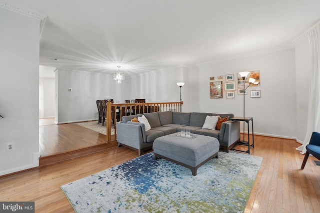 living area featuring a chandelier, baseboards, ornamental molding, and wood-type flooring