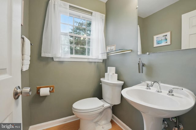 bathroom featuring a sink, wood finished floors, toilet, and baseboards