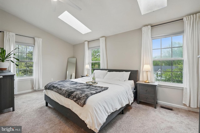 carpeted bedroom featuring baseboards, visible vents, lofted ceiling with skylight, and multiple windows