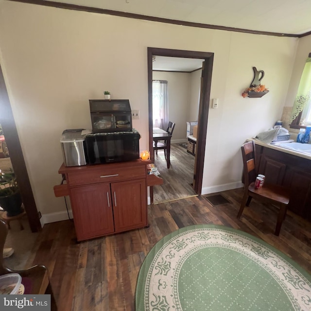 interior space featuring black microwave, wood finished floors, crown molding, and baseboards