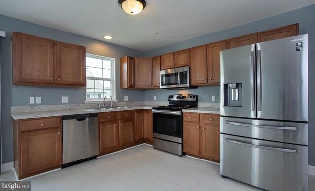 kitchen featuring light countertops, brown cabinetry, appliances with stainless steel finishes, and a sink