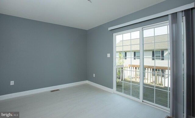 spare room with wood finished floors, visible vents, and baseboards
