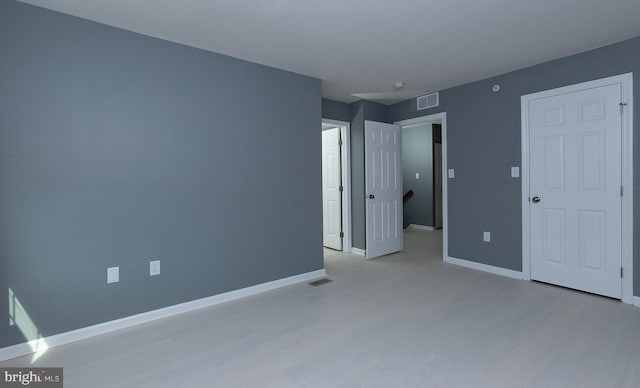 unfurnished bedroom featuring light wood-type flooring, visible vents, and baseboards