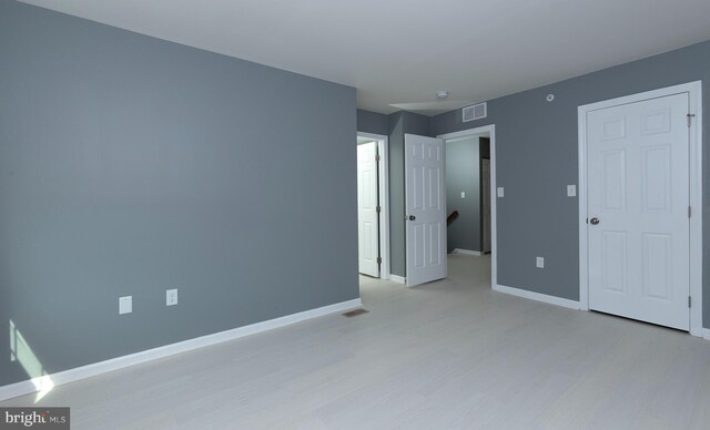 unfurnished bedroom with light wood finished floors, baseboards, and visible vents