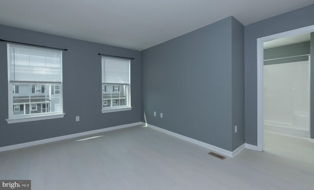 unfurnished bedroom with wood finished floors, baseboards, and multiple windows