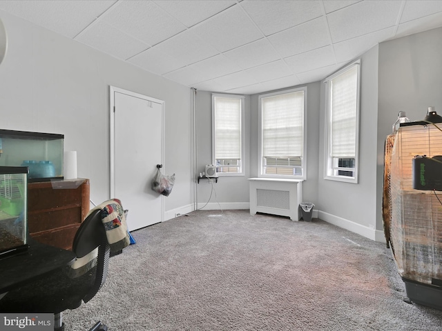 interior space with baseboards, carpet flooring, a paneled ceiling, and radiator heating unit