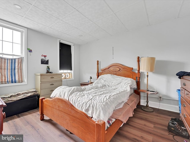 bedroom featuring a paneled ceiling, baseboards, and wood finished floors