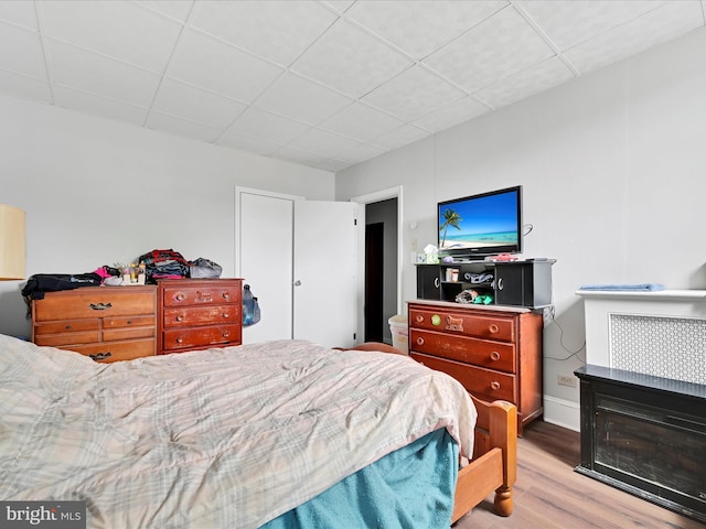 bedroom with a drop ceiling and wood finished floors