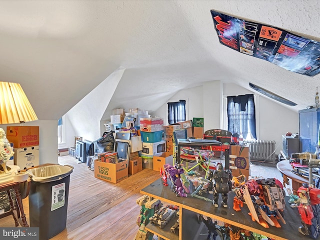 additional living space with a textured ceiling, wood finished floors, and lofted ceiling