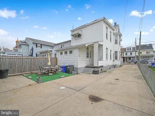 rear view of house featuring a fenced backyard, a chimney, a patio area, and a residential view