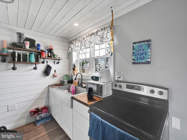 kitchen with white microwave, wooden walls, stainless steel electric range, white cabinets, and wooden ceiling