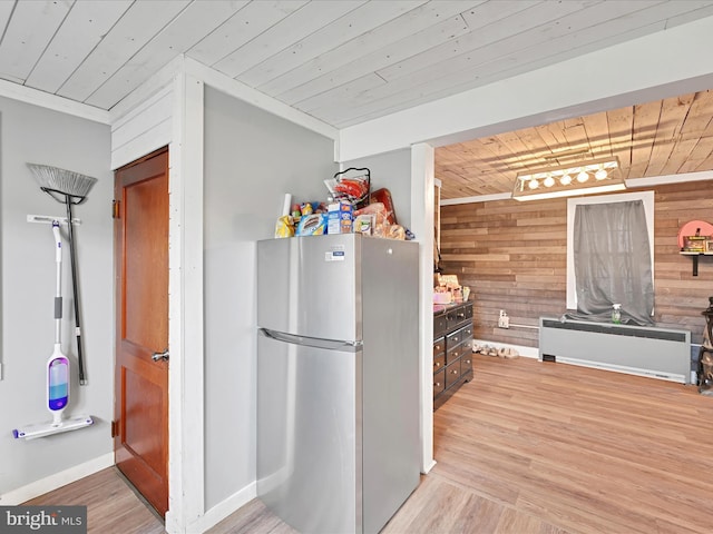 kitchen with freestanding refrigerator, wooden walls, wood ceiling, and light wood-style floors
