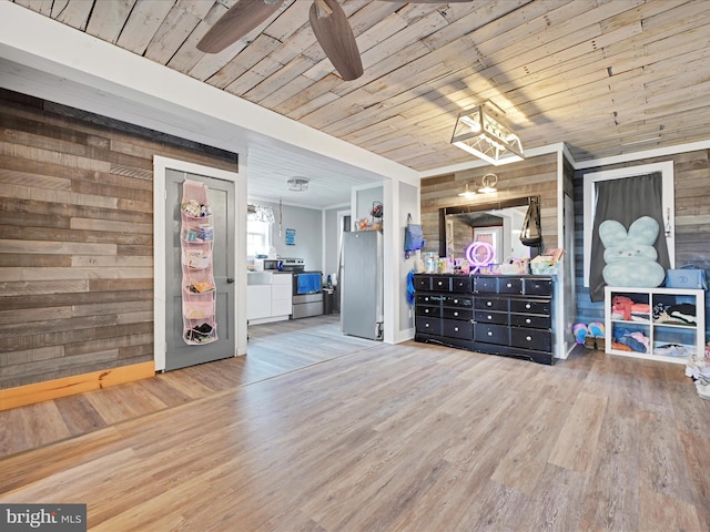unfurnished bedroom with an inviting chandelier, wood walls, freestanding refrigerator, wood finished floors, and wood ceiling