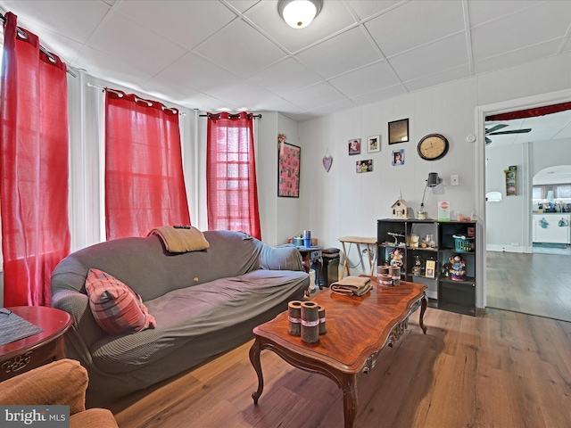 living area featuring a paneled ceiling and wood finished floors