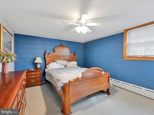 bedroom featuring concrete block wall, ceiling fan, and a baseboard heating unit