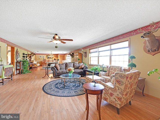 living area featuring a textured ceiling, ceiling fan, plenty of natural light, and wood finished floors