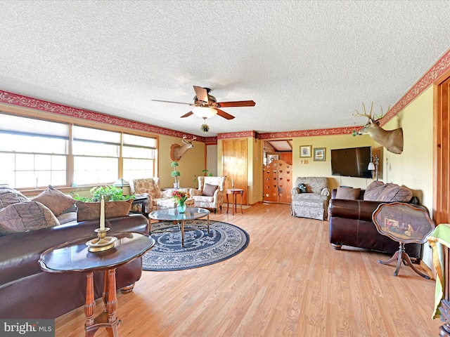 living area featuring a ceiling fan, a textured ceiling, and light wood-type flooring