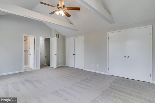 unfurnished bedroom featuring visible vents, lofted ceiling with beams, carpet, and multiple closets