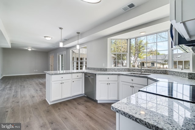 kitchen with a sink, a peninsula, white cabinetry, stainless steel dishwasher, and wood finished floors
