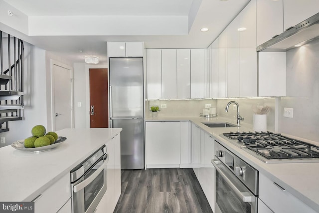 kitchen featuring stainless steel appliances, light countertops, modern cabinets, a sink, and white cabinetry