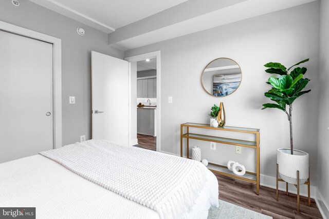 bedroom featuring baseboards, wood finished floors, and a sink
