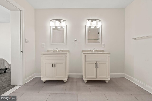 full bathroom featuring two vanities, tile patterned flooring, baseboards, and a sink