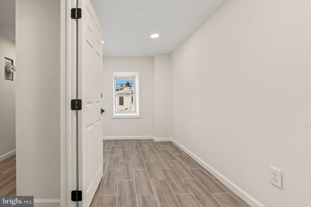 hall with wood finished floors, baseboards, and recessed lighting