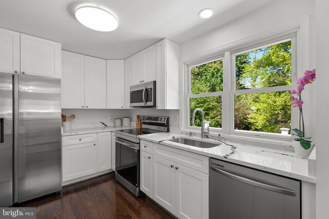 kitchen featuring light stone counters, white cabinetry, a sink, appliances with stainless steel finishes, and dark wood-style flooring