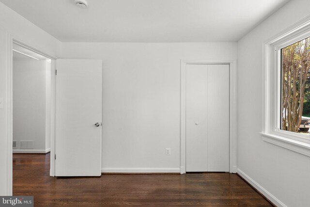 unfurnished bedroom featuring baseboards, visible vents, and dark wood-style flooring