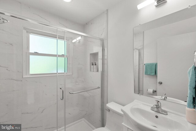bathroom featuring a marble finish shower, toilet, and vanity