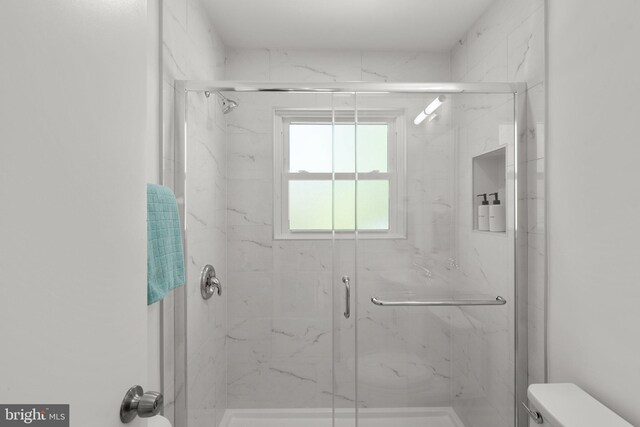 full bathroom with a marble finish shower and toilet