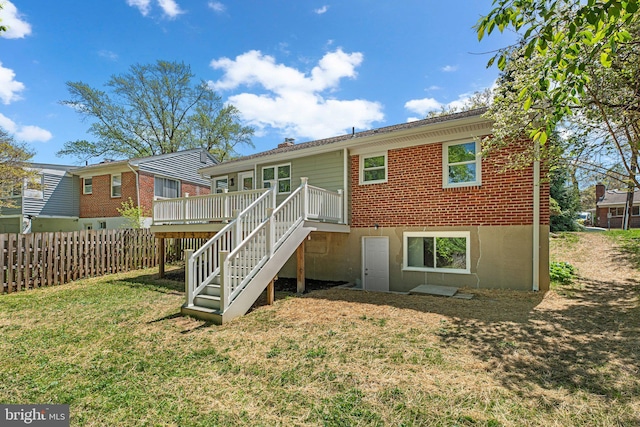 rear view of house with a wooden deck, a yard, stairs, brick siding, and fence