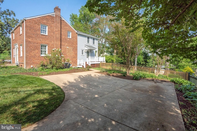 rear view of house with a chimney, brick siding, fence, and a lawn