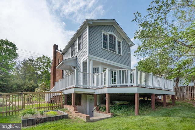 back of property featuring fence, a chimney, a deck, a yard, and stairs