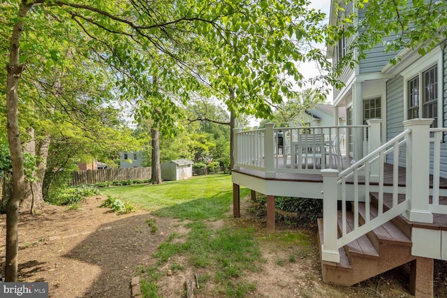 view of yard featuring a deck, an outbuilding, a storage shed, and fence