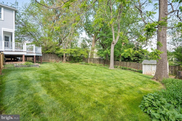 view of yard featuring a fenced backyard, a deck, a storage unit, and an outdoor structure