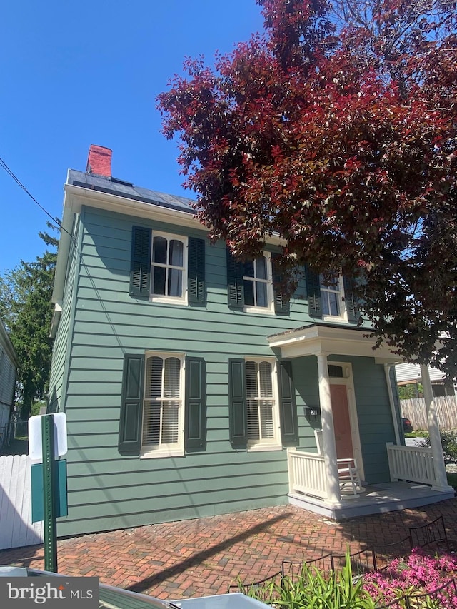 27 E Salisbury St, Williamsport, MD 21795 - view of front of property with a chimney, fence, solar panels, and covered porch