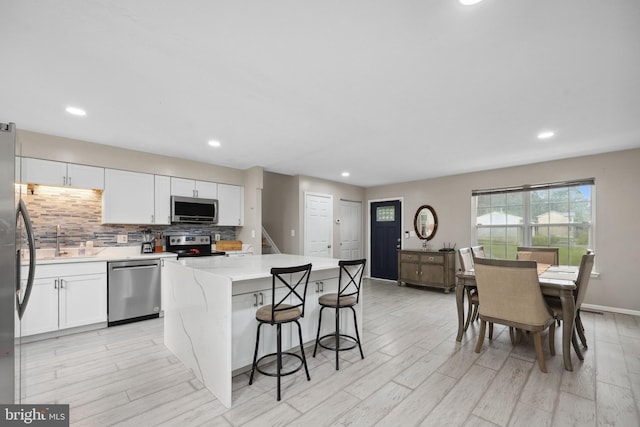 66 Vista Woods Rd, Stafford, VA 22556 - kitchen featuring stainless steel appliances, white cabinetry, a kitchen breakfast bar, a center island, and backsplash