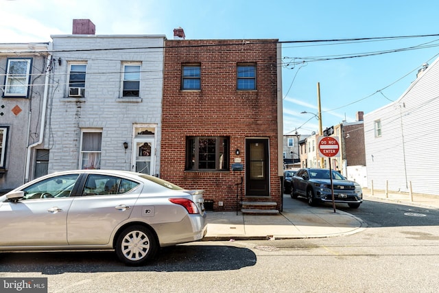 townhome / multi-family property with brick siding, cooling unit, and a chimney
