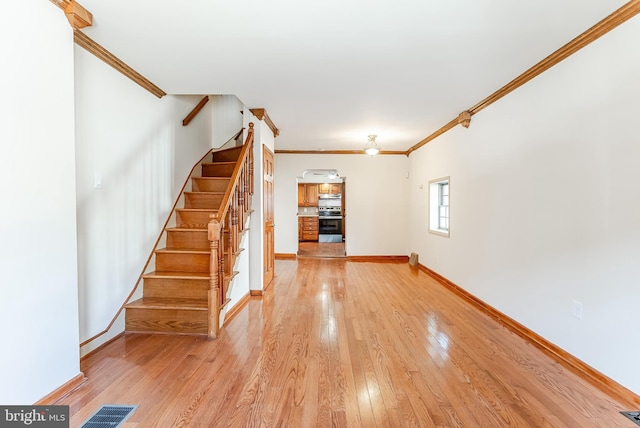 staircase with baseboards, hardwood / wood-style flooring, visible vents, and crown molding