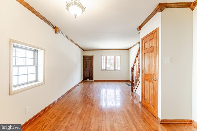 interior space featuring baseboards, light wood-style floors, and crown molding