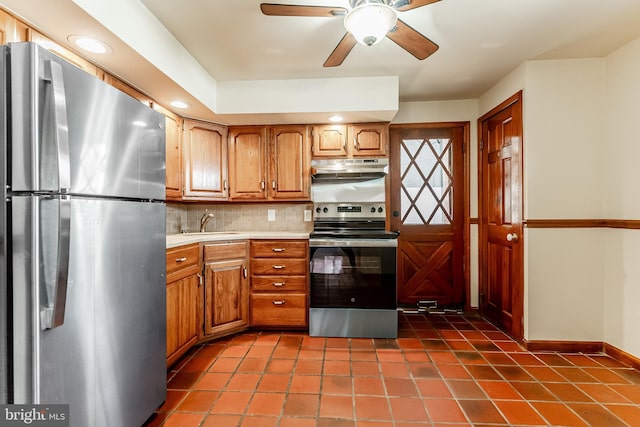 kitchen with a sink, decorative backsplash, stainless steel appliances, light countertops, and under cabinet range hood