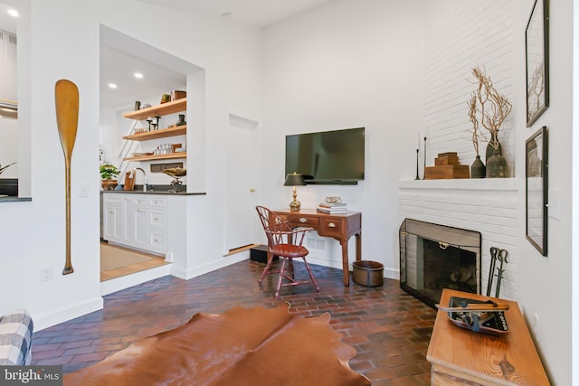 interior space with recessed lighting, brick floor, baseboards, a towering ceiling, and a fireplace