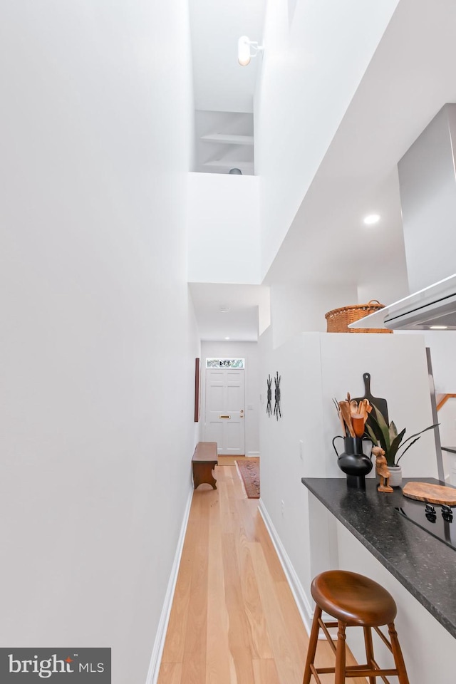 corridor featuring light wood-style flooring and baseboards