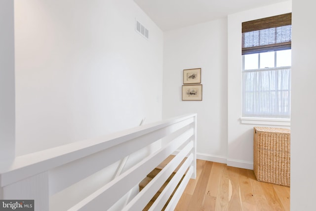 hall featuring an upstairs landing, visible vents, baseboards, and light wood-style flooring